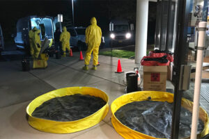 A clean up crew in hazmat suits decontaminate an area