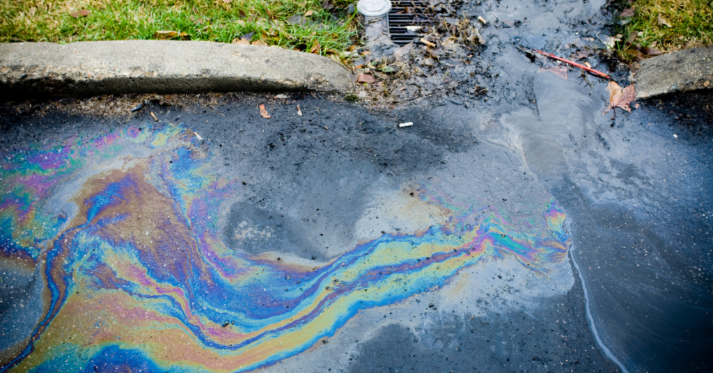 Oil spill moving towards a drain on a road.